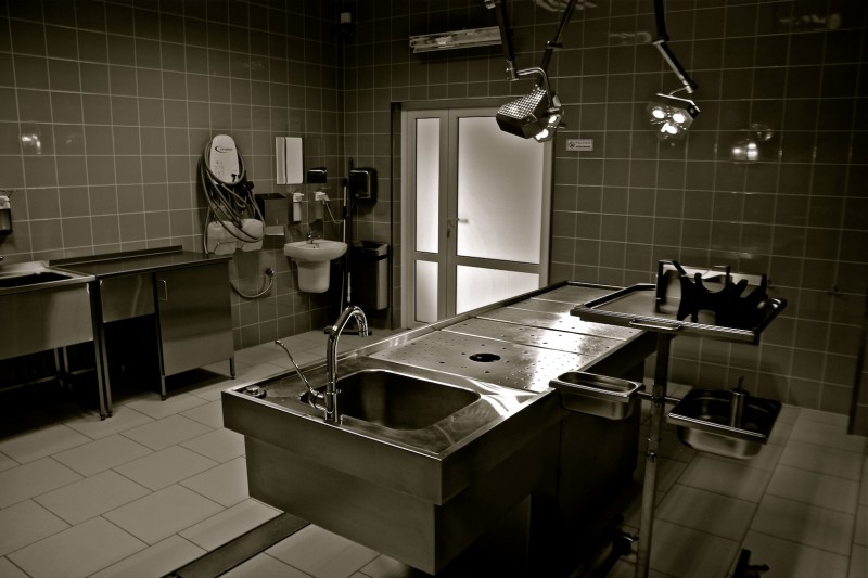 Autopsy room with stainless steel examination table and surgical lighting
